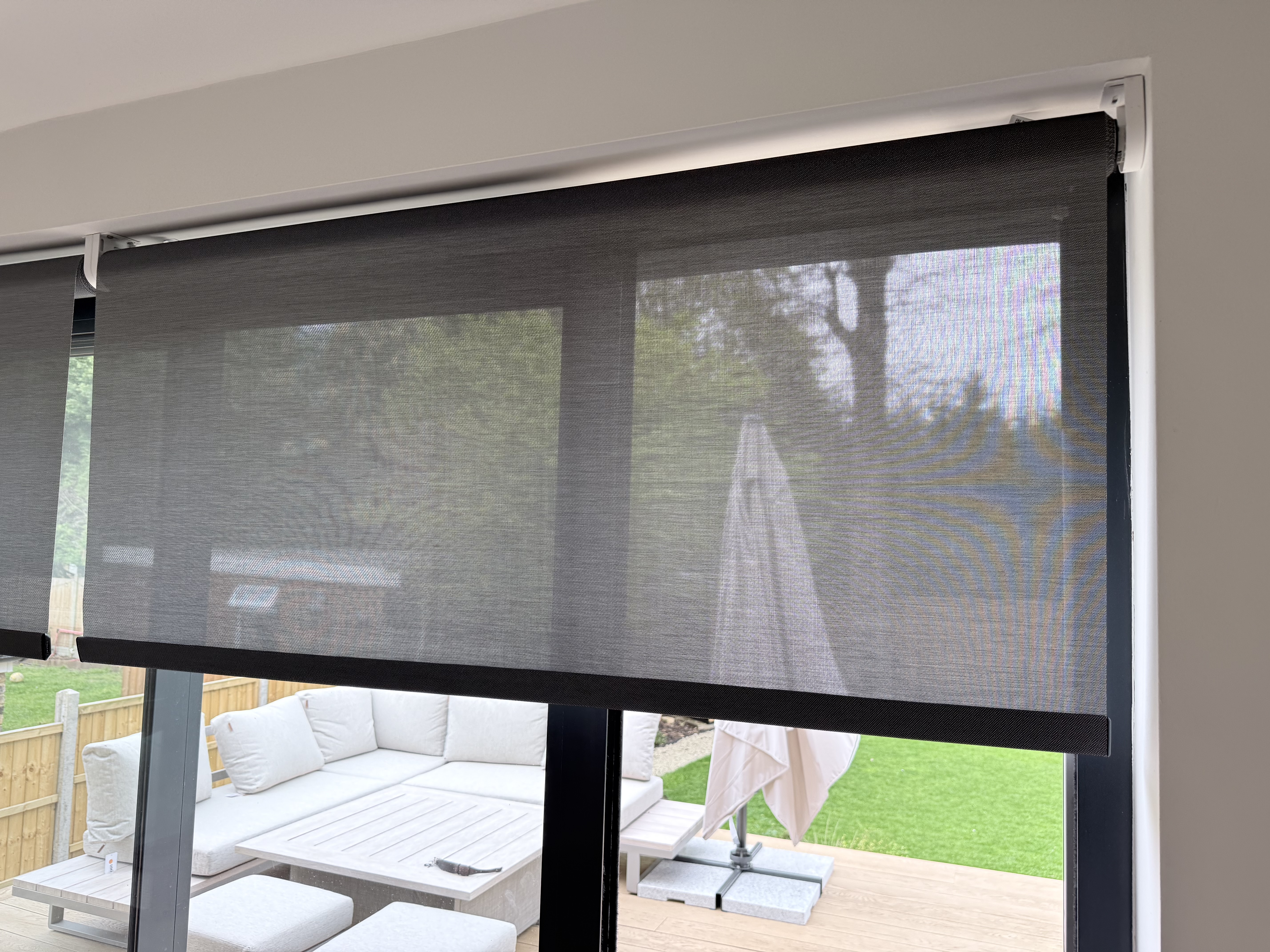 Motorised roller blinds on large glazed doors overlooking a garden terrace